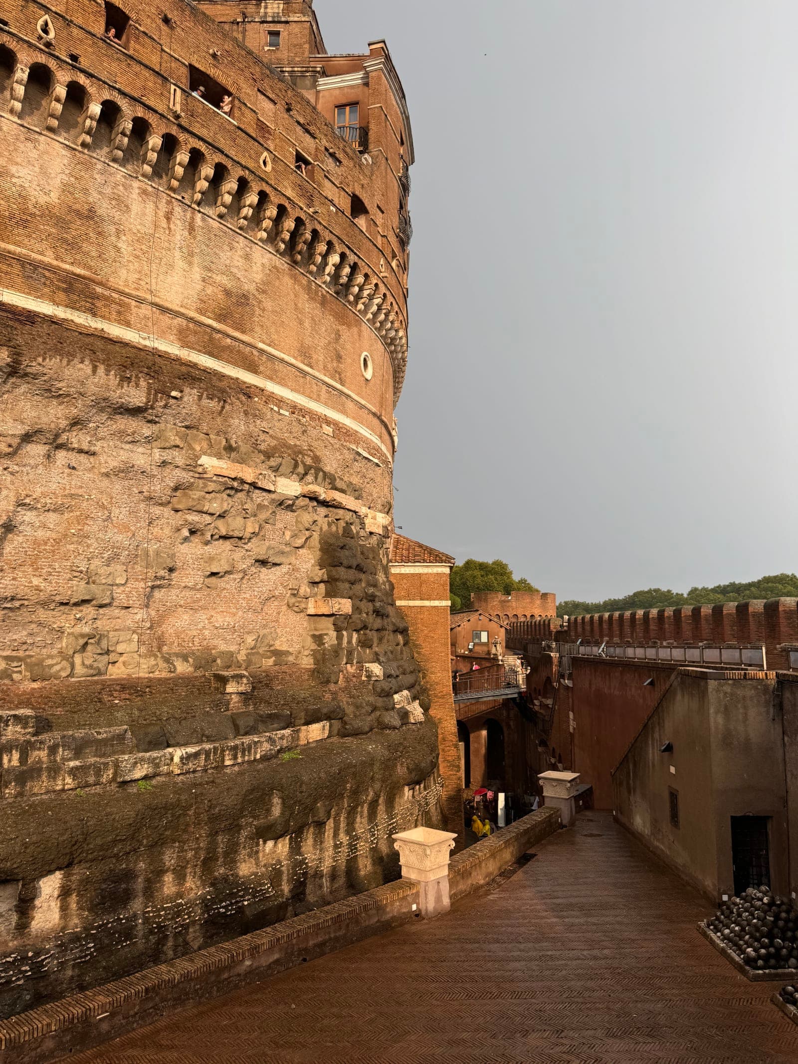 Close-up view of the ancient curved walls of Castel Sant'Angelo in Rome, Italy, with a narrow walkway alongside — photo by Abdullah Al-Marweai